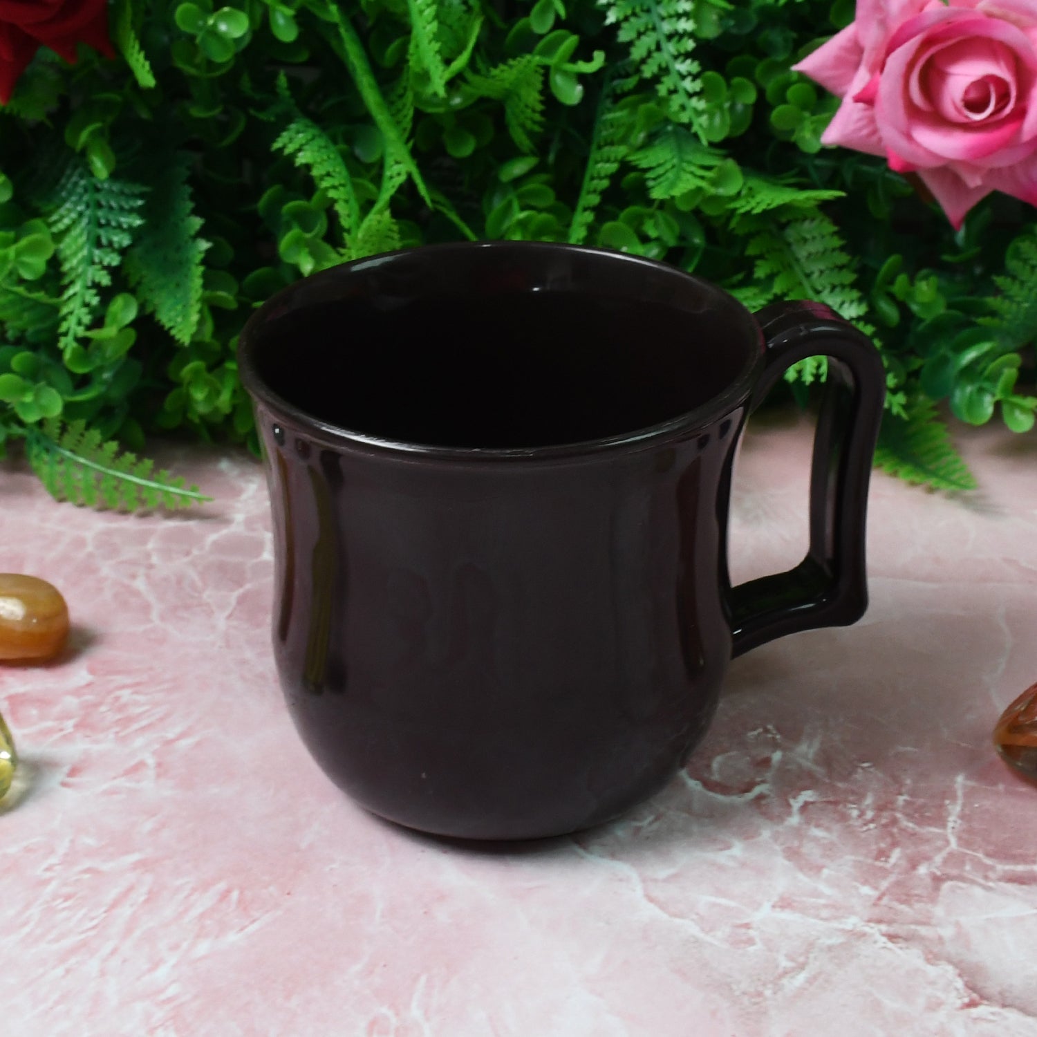 Black plastic coffee mug on a wooden table, perfect for home or office.