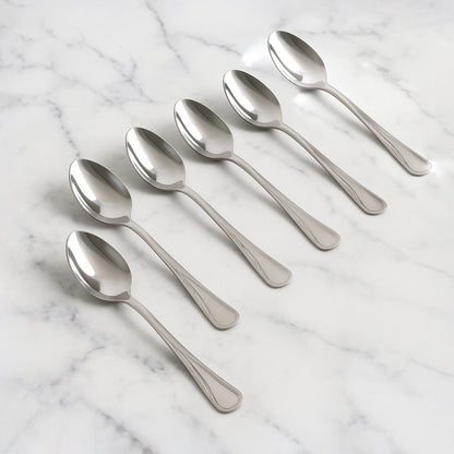 Set of 6 stainless steel dining spoons with polished finish on dining table