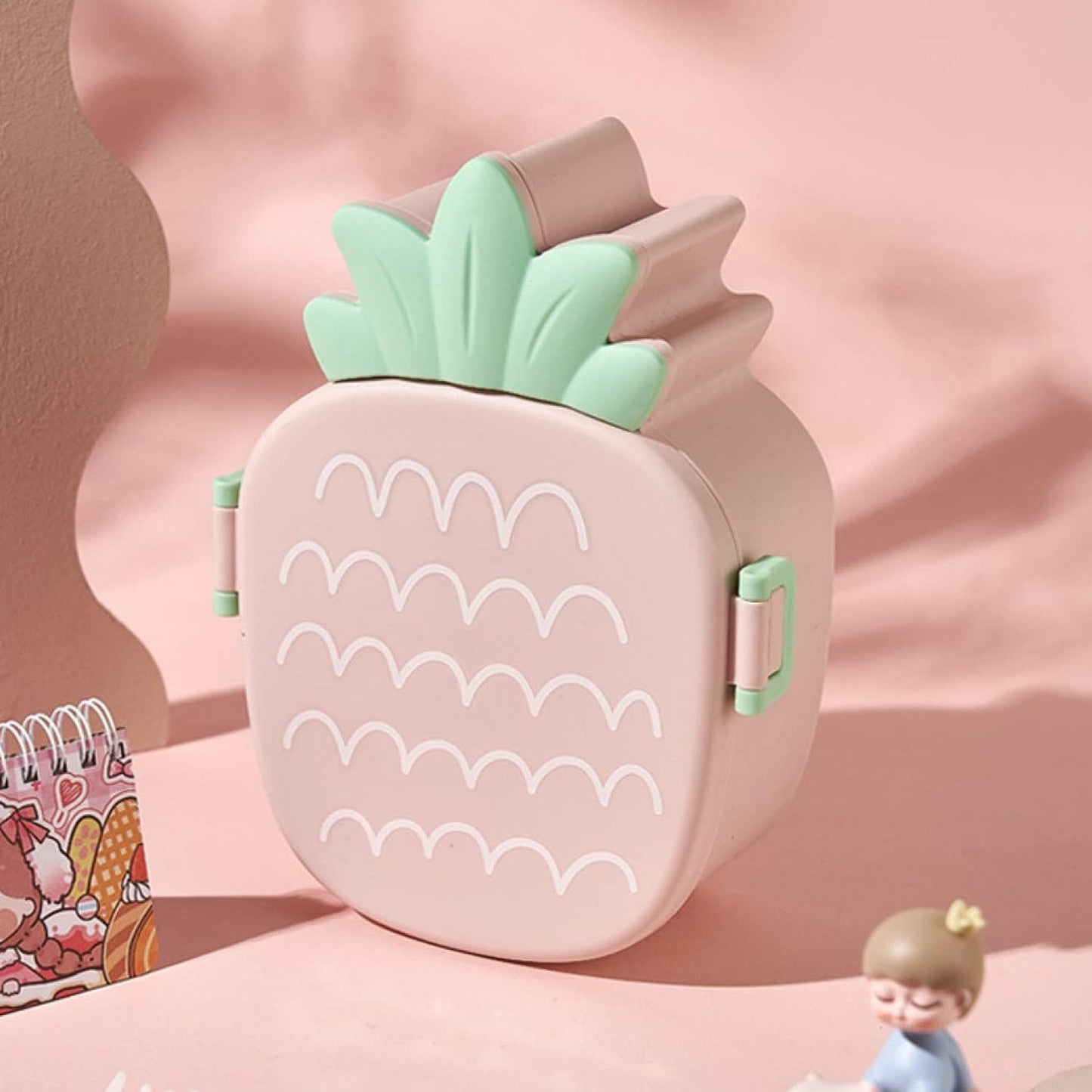 Pineapple kids bento lunch box with fork and spoon displayed on a clean surface.