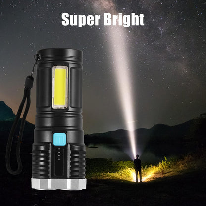 A black and silver flashlight standing upright, casting a bright beam of light into the night sky where a person stands.