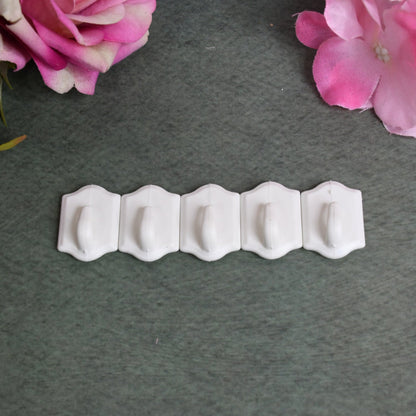 Adhesive wall hooks demonstrated holding kitchen utensils on a tiled wall.