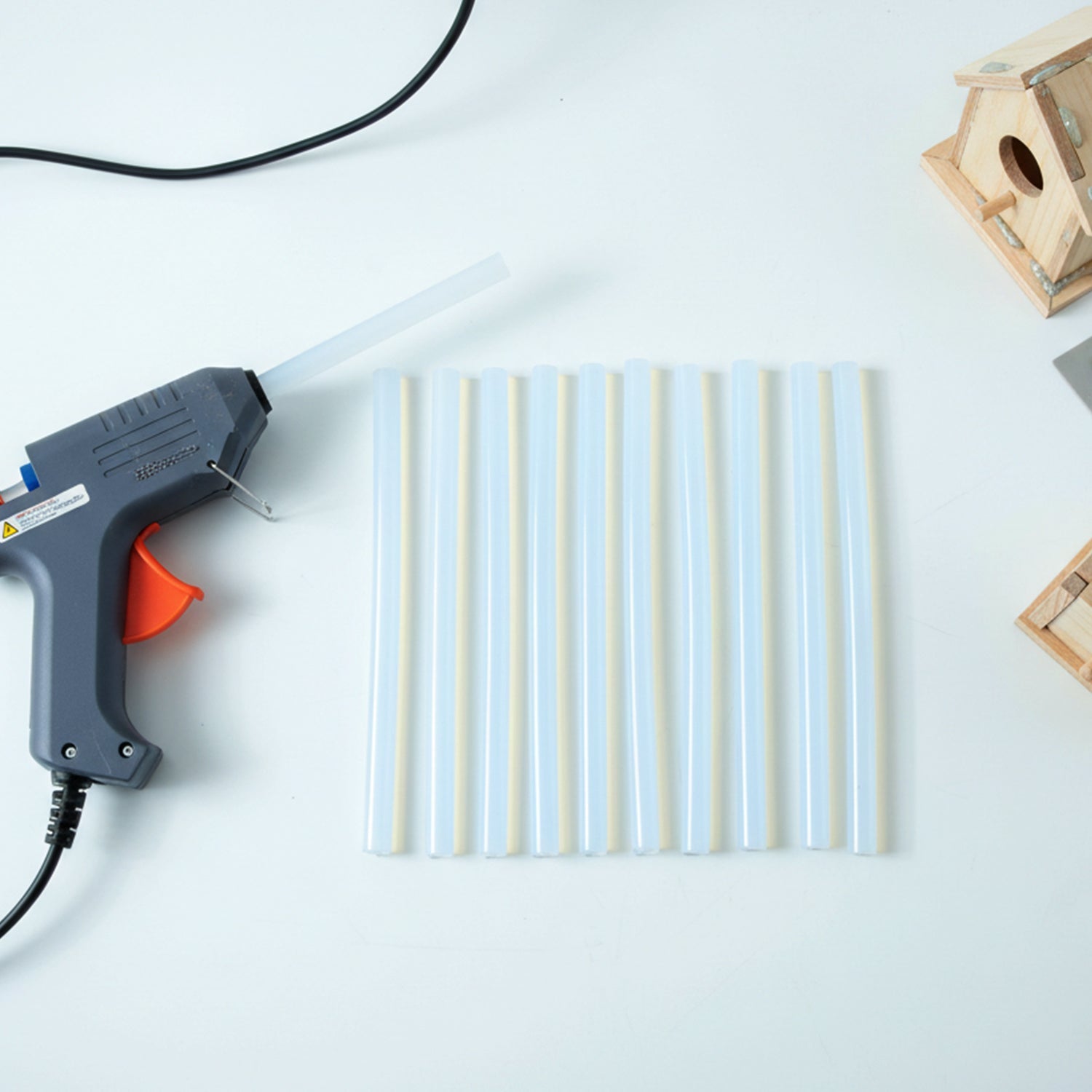 Hand using hot glue gun applying clear adhesive from stick