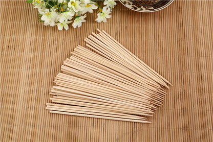 Hand holding a natural bamboo skewer with perfectly grilled meat.