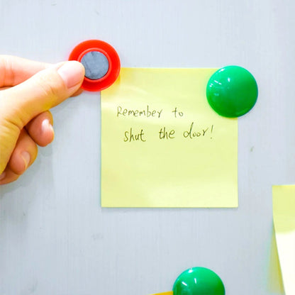Magnetic buttons adhering to a metal cabinet, demonstrating strong hold.
