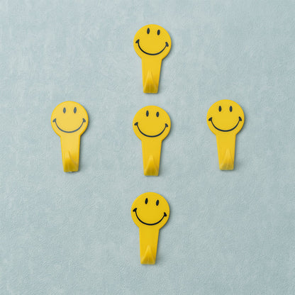 A set of five white self adhesive hooks displayed on a clean surface.