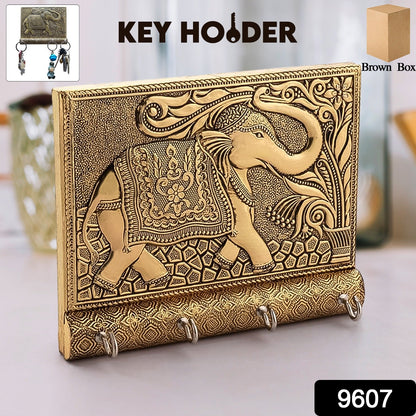Close-up of the polished gold elephant head and hooks on the wooden key holder.