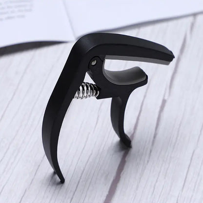 Guitar capo and pick holder positioned on a guitar neck, ready for playing.