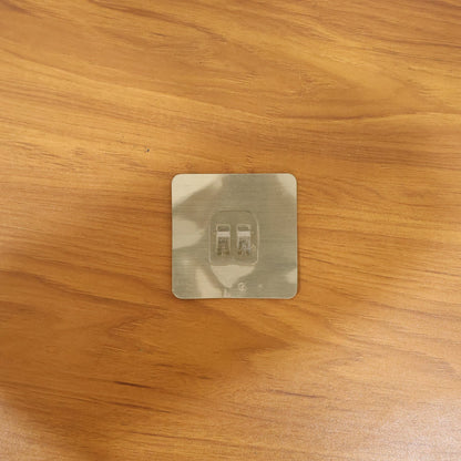 Transparent adhesive wall hook in a real-life home setting, holding various items.