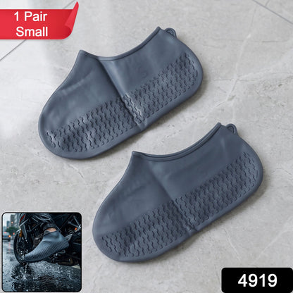 A pair of gray silicone foot coverings with textured soles on a tiled floor, with a red